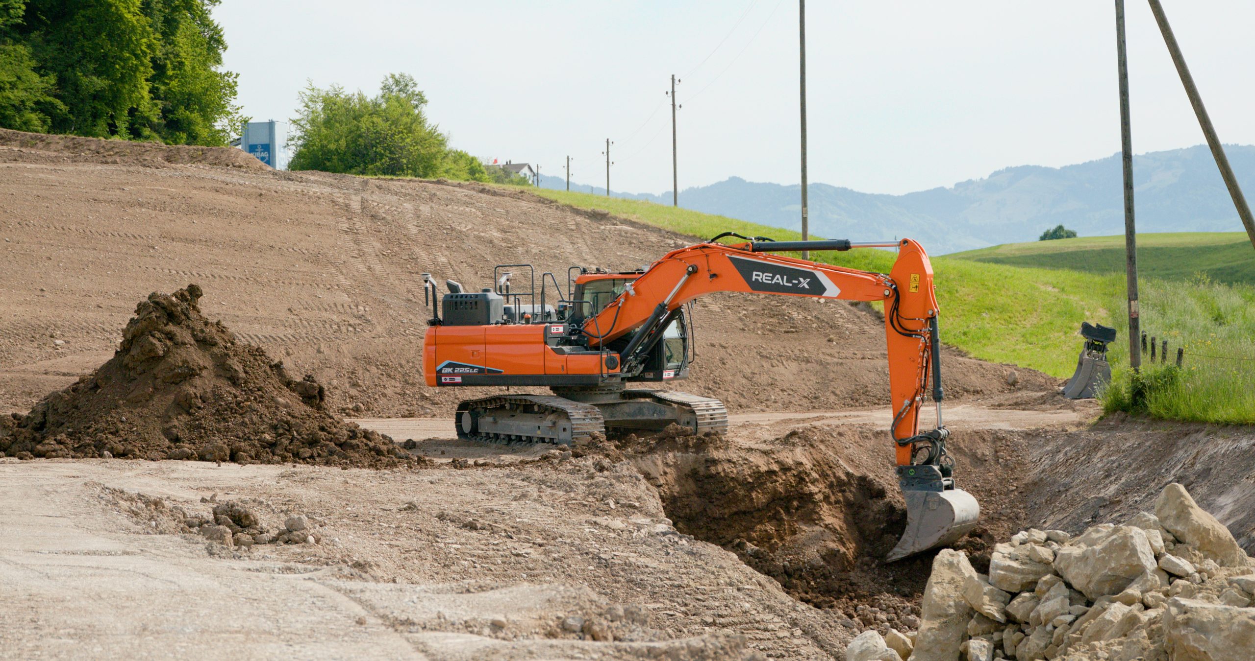 Il nuovo Develon DX225LC-7X con sistema autonomo Real-X impegnato nello scavo della trincea da 300 metri per il consolidamento delle pendici della ex cava KIBAG.