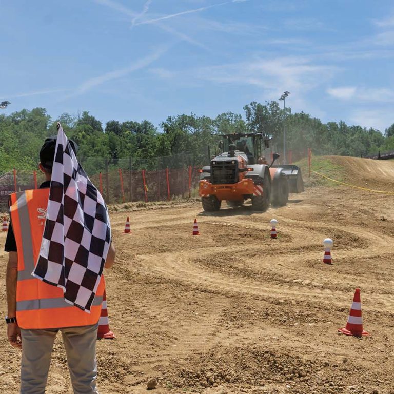 La pala gommata HITACHI ZW220-7 affronta il tracciato del circuito Monte Coralli di Faenza, impegnata nella corsa a ostacoli del LANDCROS Operator Challenge.