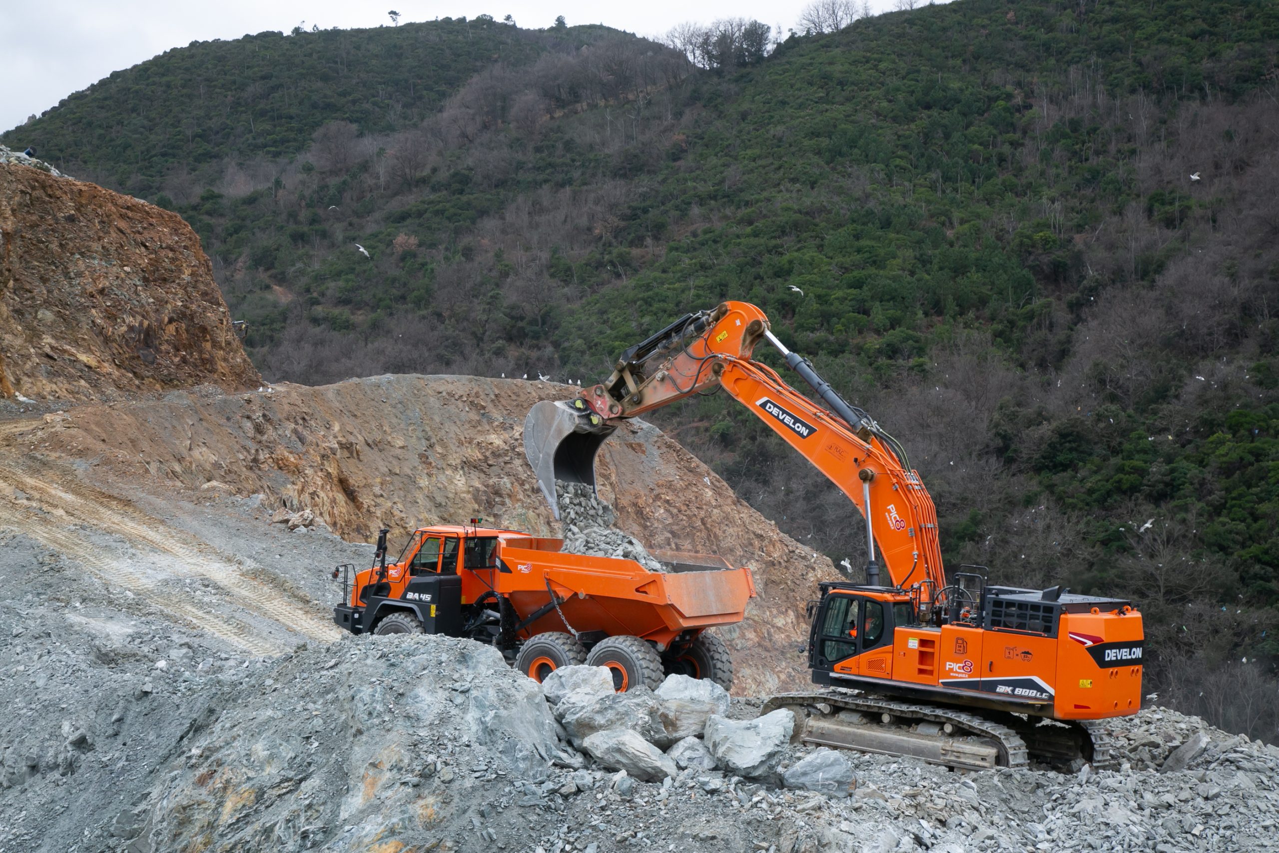 L'azione combinata dei mezzi DEVELON nel cantiere ligure: lo snodo di articolazione e la trazione 6×6 del dumper DA45-7 garantiscono la massima stabilità durante le delicate operazioni di carico.