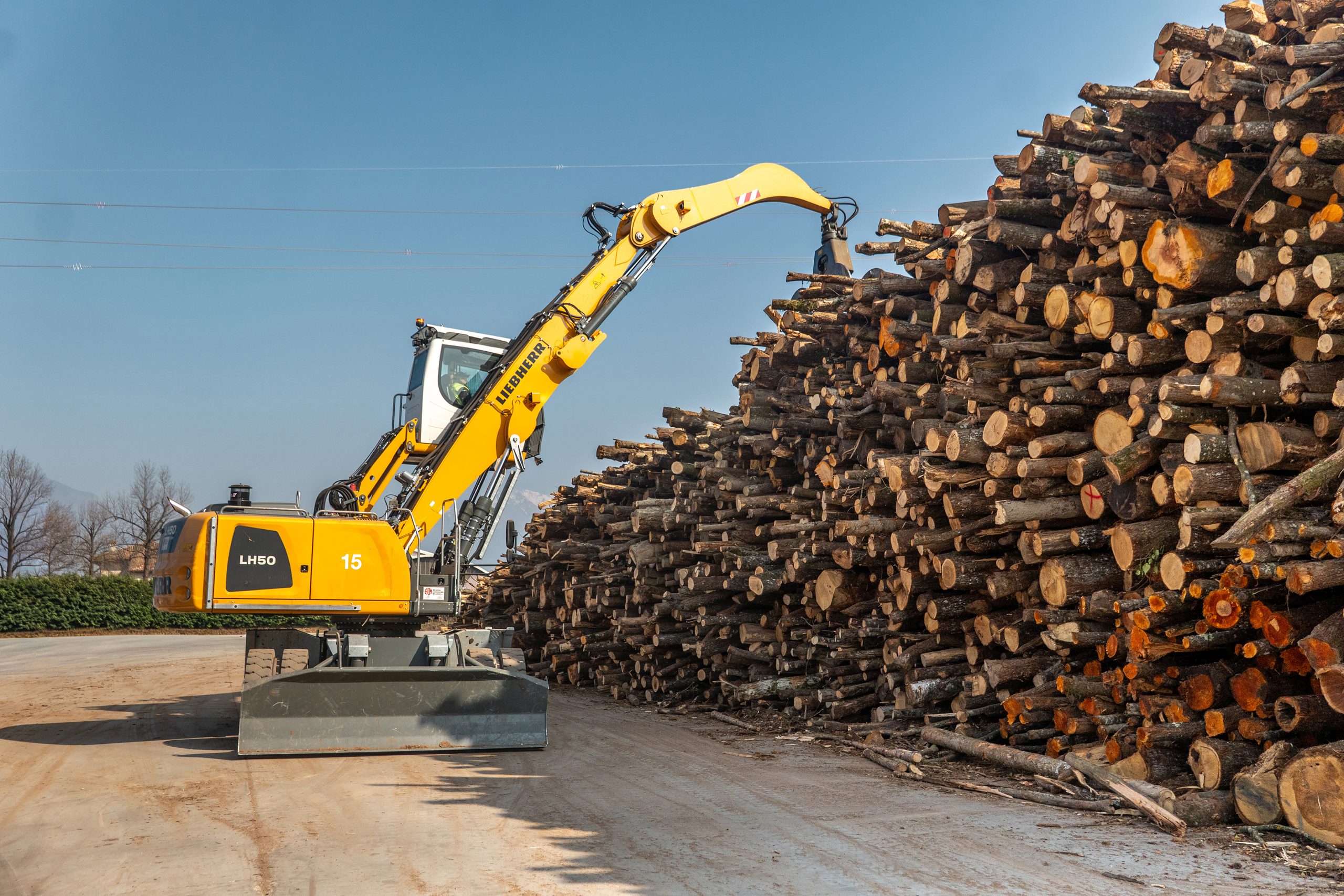 La macchina per la movimentazione del legname LH 50 M Timber Litronic accatasta i tronchi con precisione.
