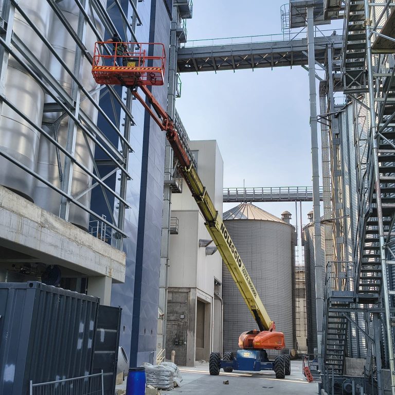 La piattaforma semovente a braccio telescopico JLG 1350SJP di EUROTECNO in azione durante le complesse operazioni di fissaggio in quota della carpenteria metallica.