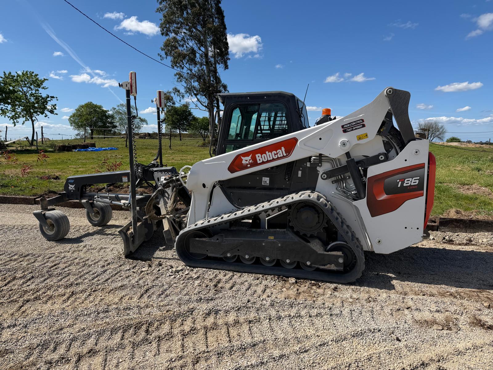 La potente pala compatta cingolata Bobcat T86 equipaggiata con livellatrice laser durante le operazioni di precisione millimetrica su un fondo ippico.