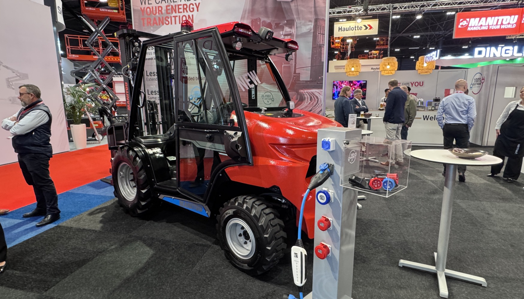 Un modello della nuova gamma di carrelli elevatori fuoristrada 100% elettrici di Manitou in mostra alla fiera APEX di Maastricht, completo di stazione e cavo di ricarica per batterie agli ioni di litio.