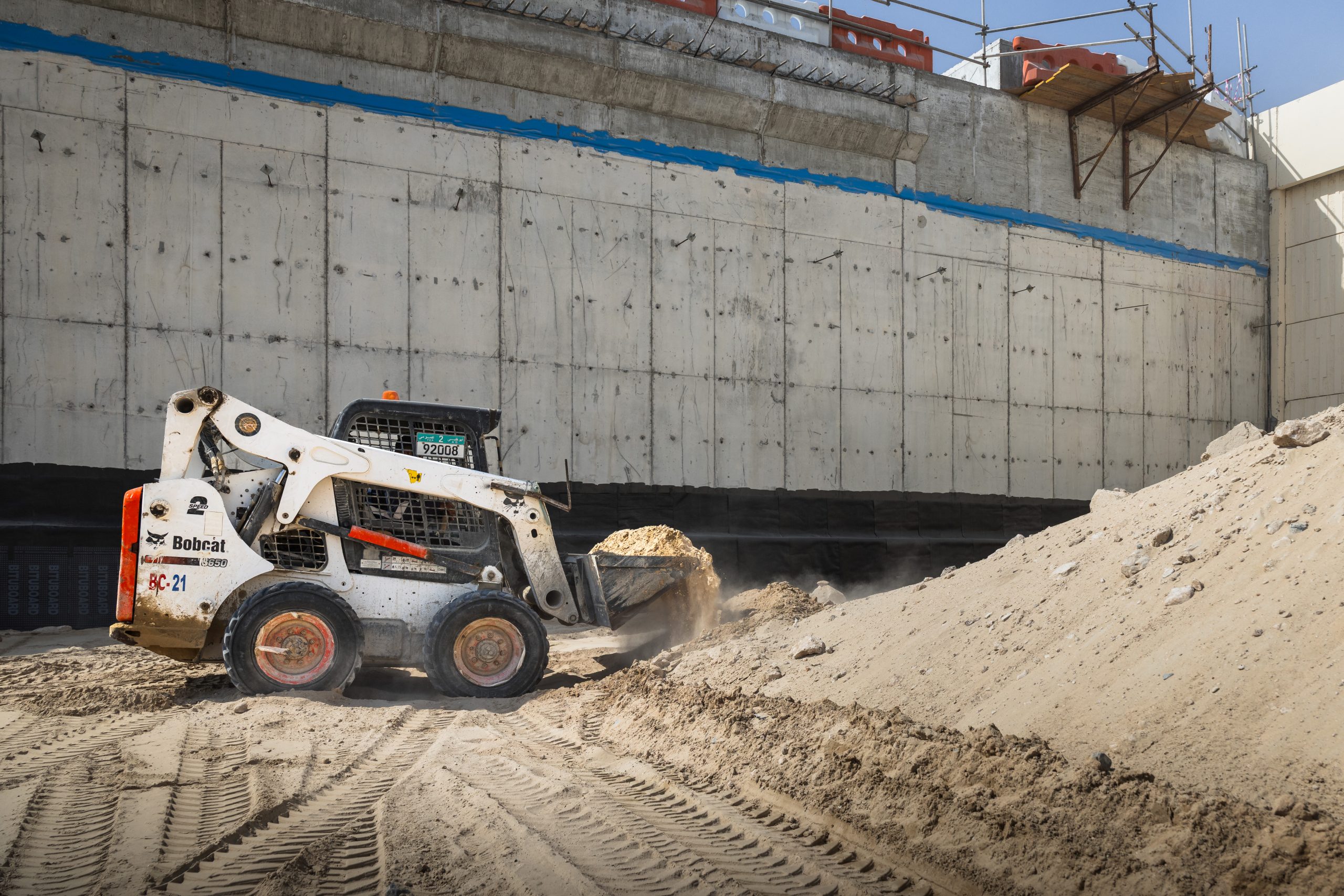 Pala compatta BOBCAT al lavoro in un cantiere ad alte temperature: macchine progettate per operare in sicurezza e con massima efficienza anche in condizioni ambientali estreme e in presenza di polvere e sabbia.