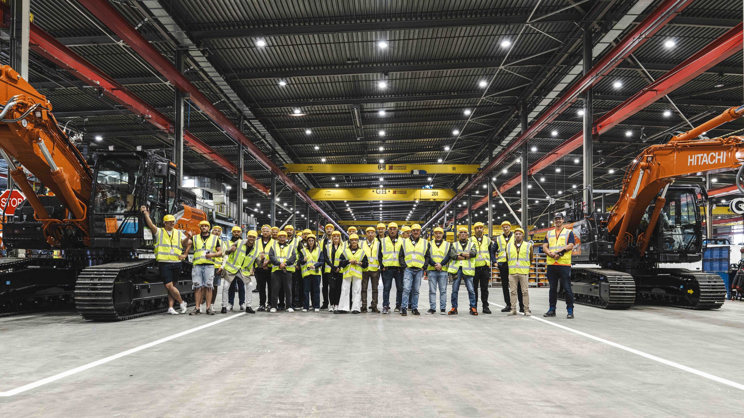 Foto di gruppo dei finalisti della LANDCROS European Operator Challenge e del vincitore Guy Jacobs (Belgio), immortalati insieme alle macchine Hitachi nello stabilimento di Amsterdam.