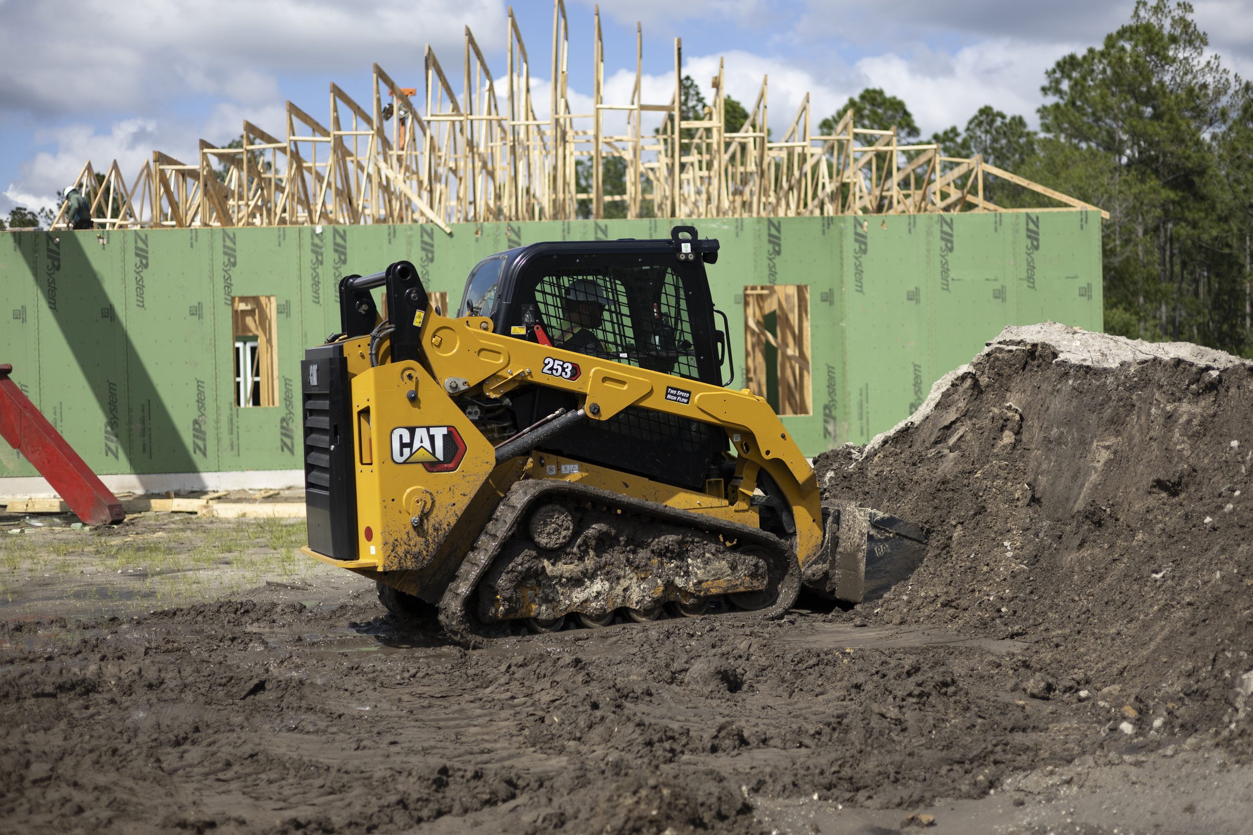 Il caricatore cingolato compatto Cat® 253 al lavoro in cantiere per attività di livellamento e scavo, grazie alla forte aderenza dei cingoli e del sottocarro monoblocco.