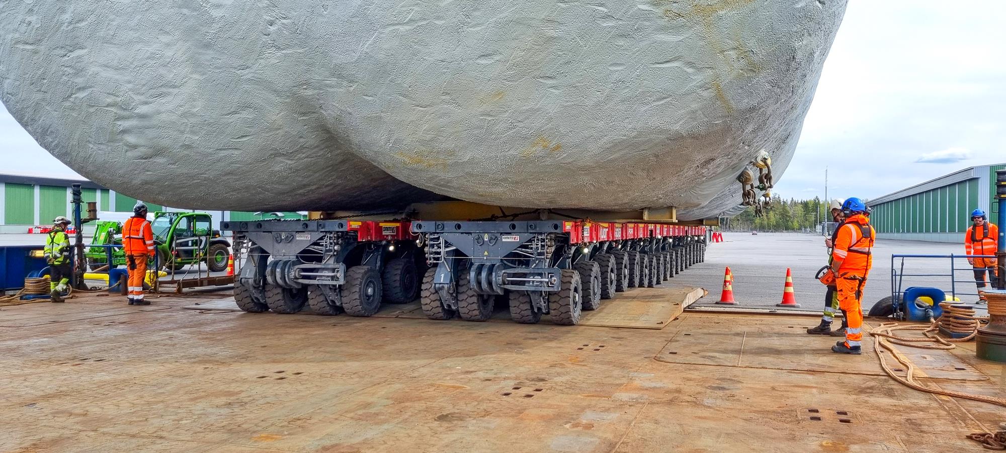 I semoventi Cometto su 36 linee d'assi in azione sotto l'enorme serbatoio GNL.