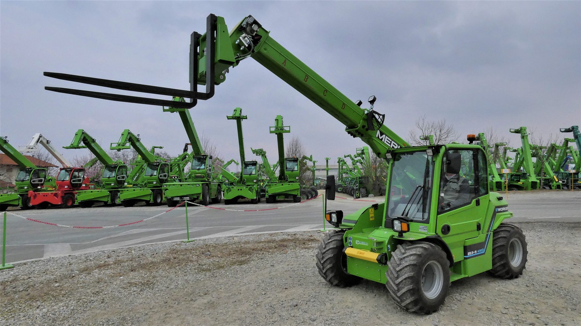 Il MERLO e-Worker con braccio telescopico sollevato e forche montate sull'interfaccia di attacco rapido, che evidenzia la capacità di sollevamento fino a 4,8 metri.